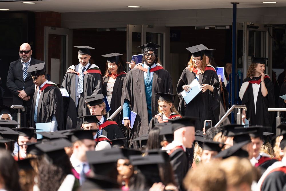 A group of people in caps and gowns leave the Octagon to join the crowd of other graduates