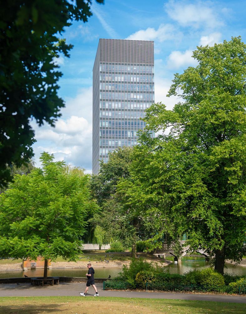 The Art Tower with trees and Weston Park pond in the foreground, the sky is blue and the sun is shining