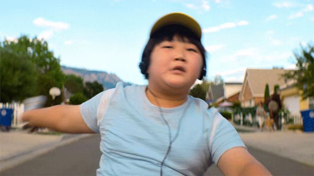 a young boy wearing headphones and a hat is riding a bike down the street