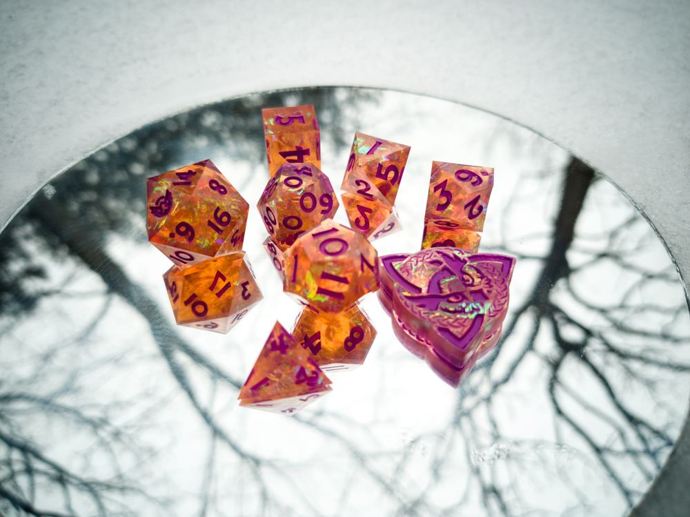 Firey orange dice with purple inking on a mirror in a wintery setting