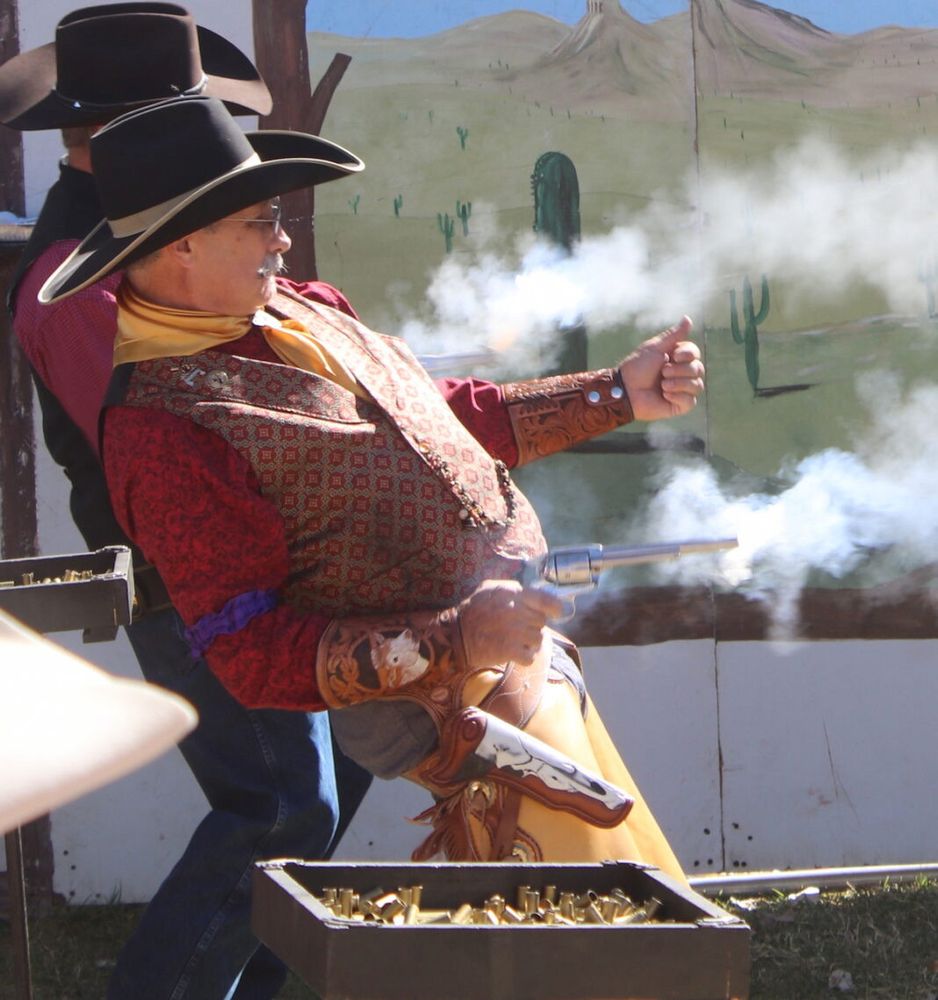 A man in a hat quickly firing a gun from the hip in a game of Quick Draw.