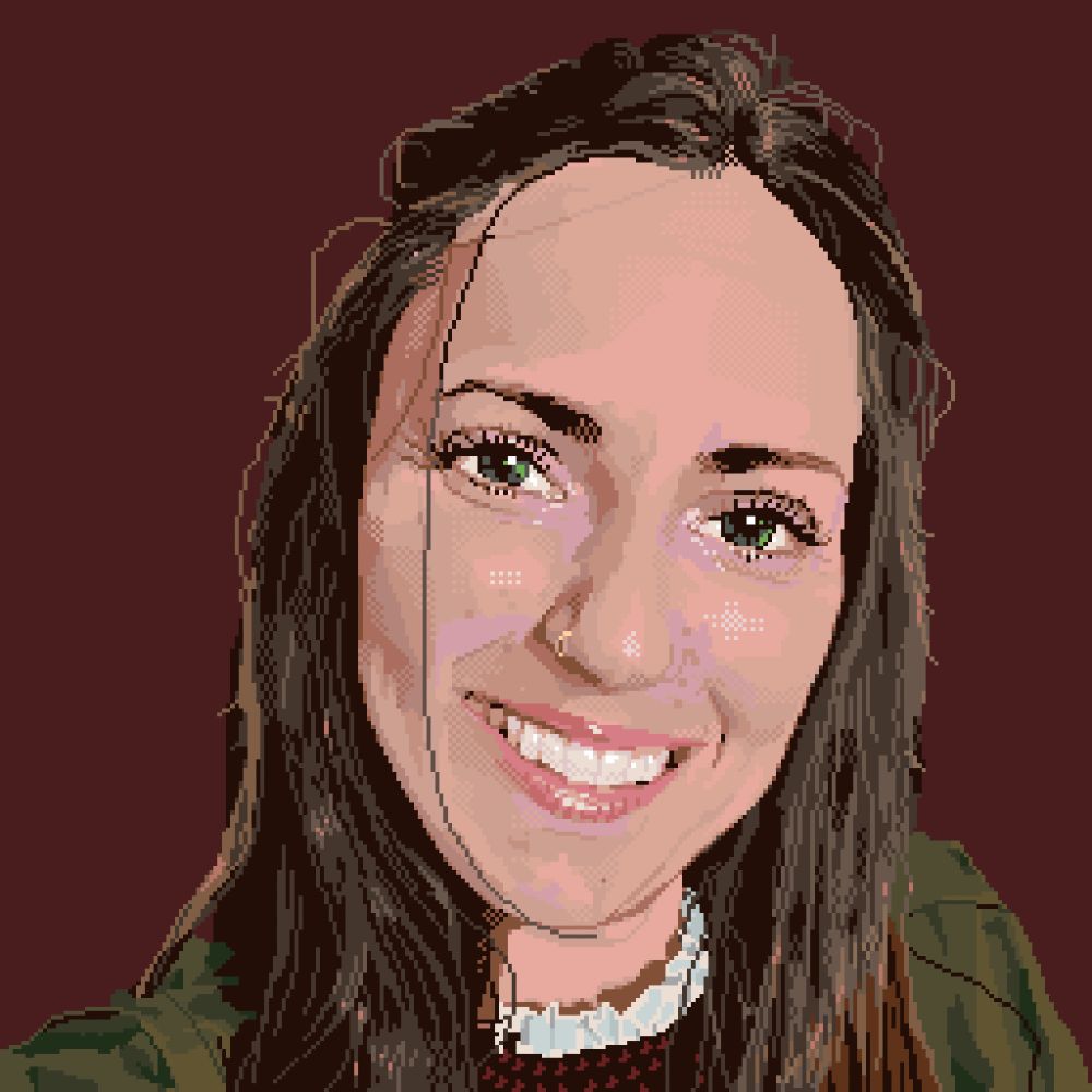 Portrait of a woman. Point of view of the camera in a selfy. There is a flat dark red background. She has long brown hair, green eyes, and a big smile. She’s wearing a red houndstooth dress with a frilly white neck under an army green jacket.