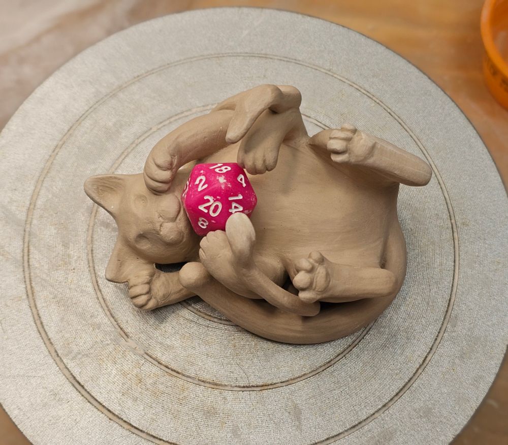 Ceramic mini sculpture of a feline monster from D&D holding a d20.