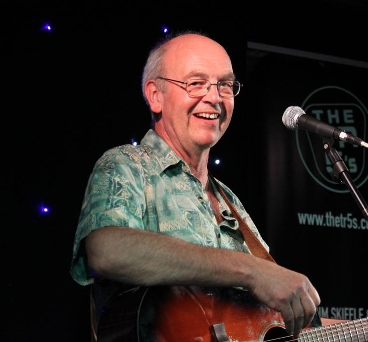 Graham Armfield onstage playing an acoustic guitar.