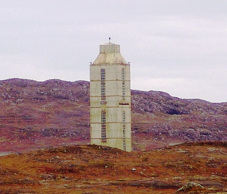 Grey, concrete multi-storey building above the Kola Superdeep Borehole, surrounded by barren low hills.