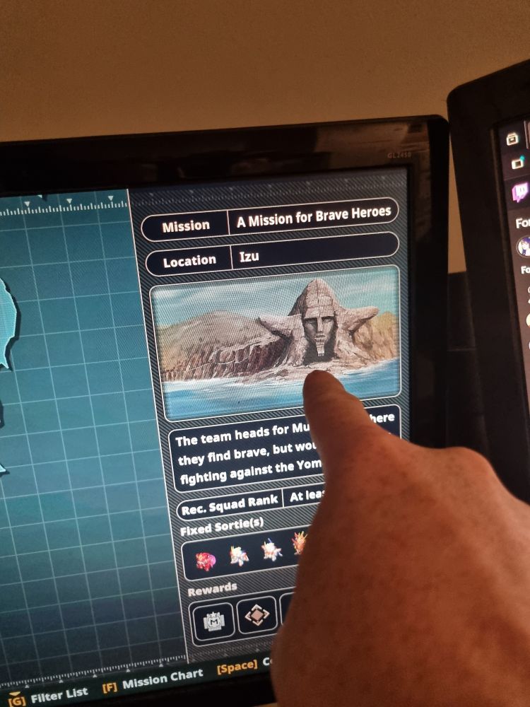 A hand pointing at a monitor showing Raideen