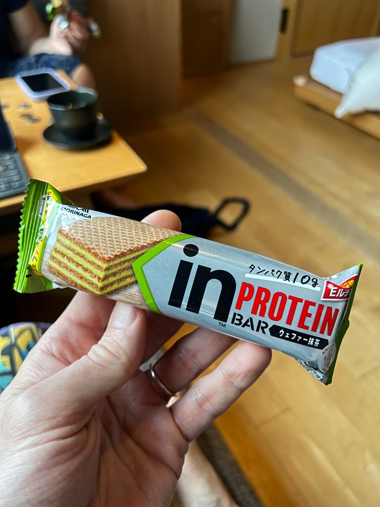 Hand holding a Japanese green tea flavored protein bar that has kit-kat like layers of wafer and green tea/protein goo