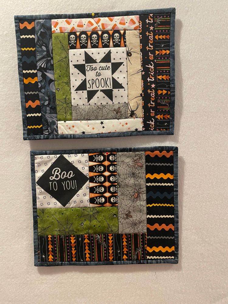 Two Spooky Mug mats with Halloween fabric, one block with words “Too cute to spook” & the other “Boo to You”. Pattern quilt as you go from Fat Quarter Shop, Limited Edition Spooky Box