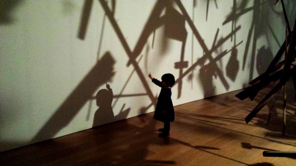 small child amazed by shadows in an art piece by Cornelia Parker