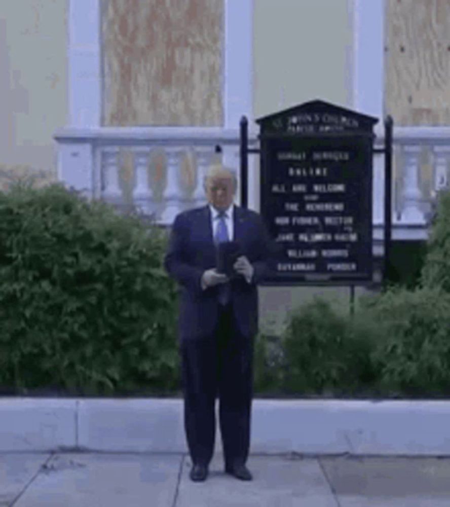 a man in a suit and tie is standing in front of a building with a sign .