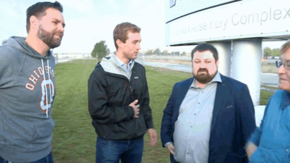 a group of men are standing in front of a sign that says complex