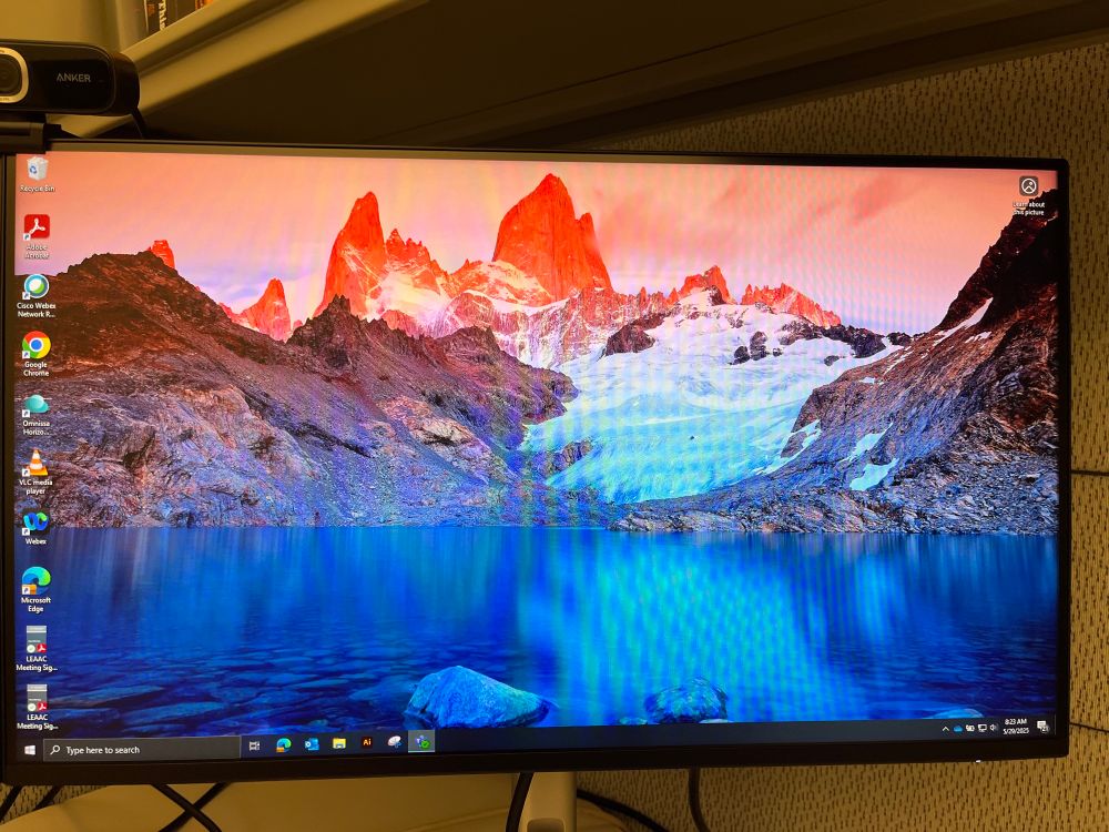 Computer background with icy lake in the bottom foreground, with a bright pink sunrise on mountain peaks rising into the background 