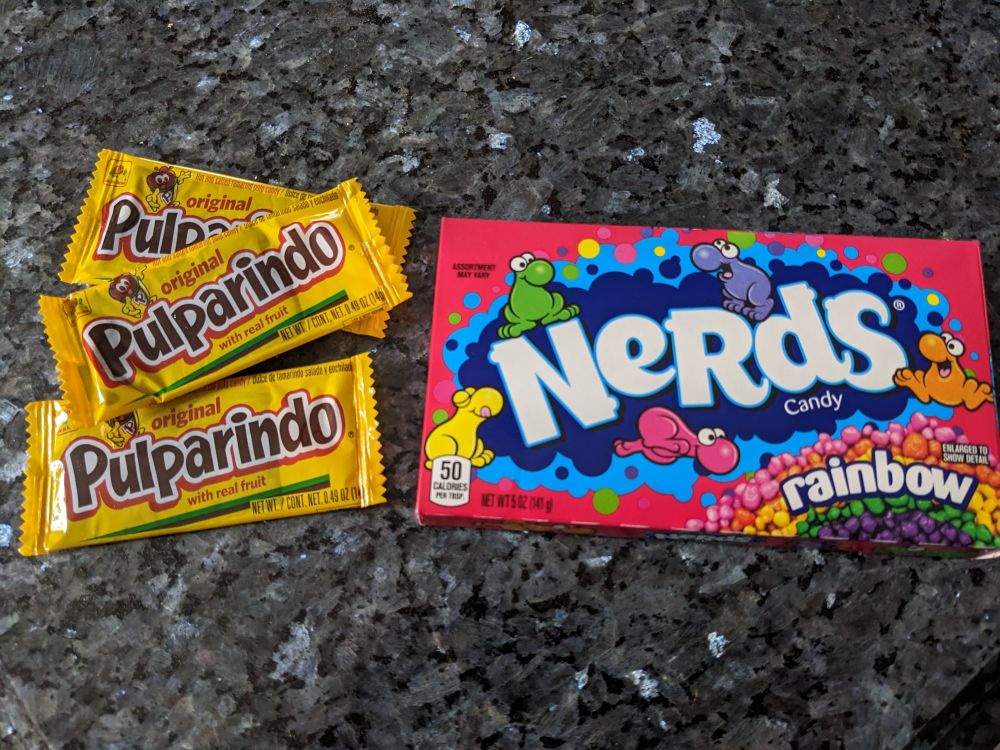 Photo of a box of rainbow nerds and a pile of pulparindo candies