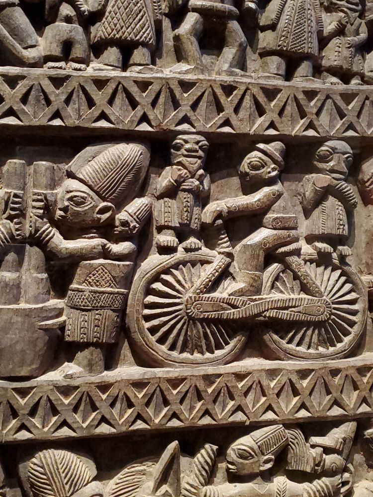 Détail de la porte sculptée: un personnage sur un vélo