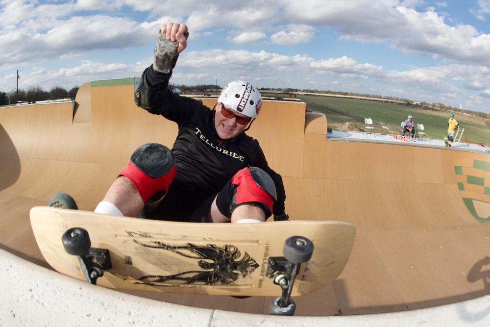 Skateboarder performs frontside grind on wooden halfpipe.