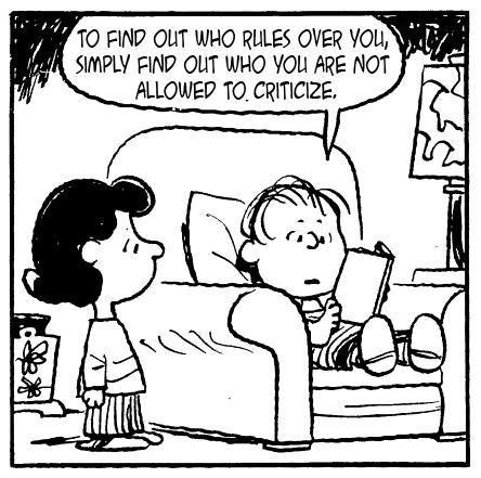 Charlie Brown reading aloud to Lucy "TO FIND OUT WHO RULES OVER YOU, SIMPLY FIND OUT WHO YOU ARE NOT ALLOWED TO CRITICIZE"