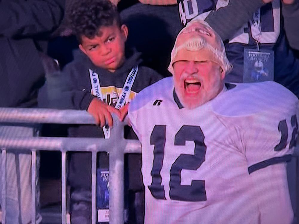 Penn State fan, yelling, and the kid behind him is perplexed 