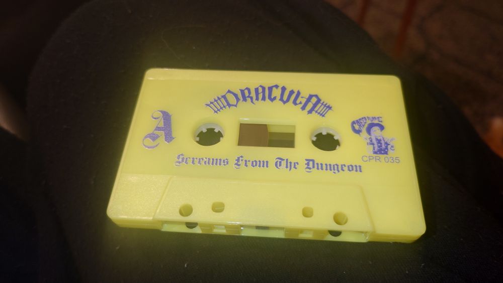 a highlighter yellow musicassette with blue inscription
"DRACULA - SCREAMS FROM THE DUNGEON" in blackletter style, with the creep purple records logo beside it 