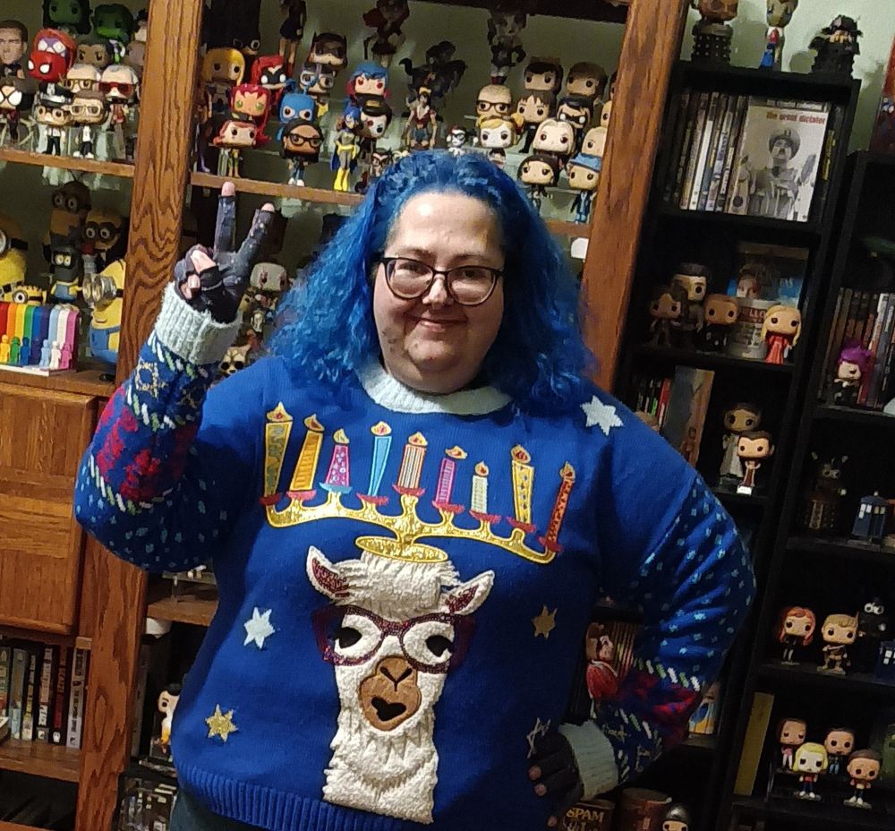 Woman with blue hair wearing a blue sweater with a llama menorah 