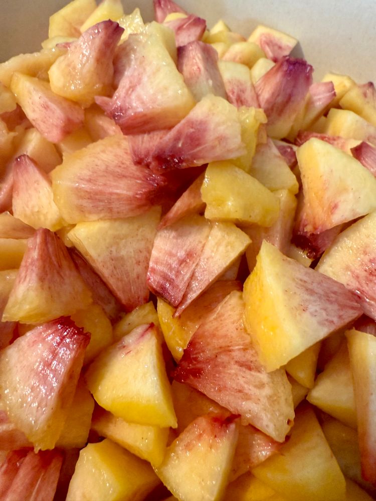 Diced peeled peaches in shades of yellow, orange, pink, and maroon 