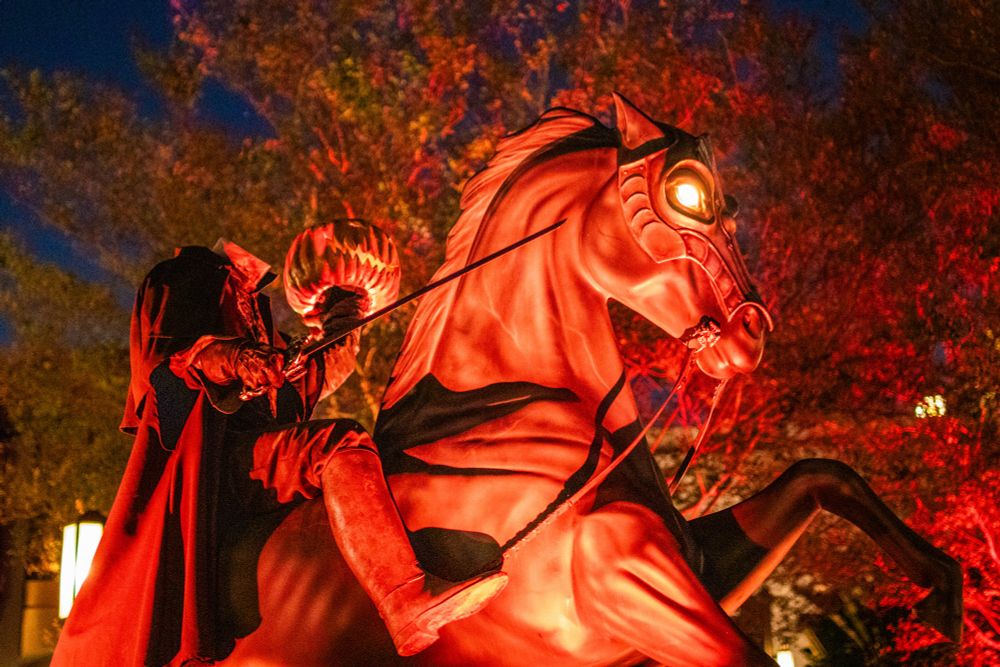 A statue of the Headless Horseman and his horse bathed in orange light.