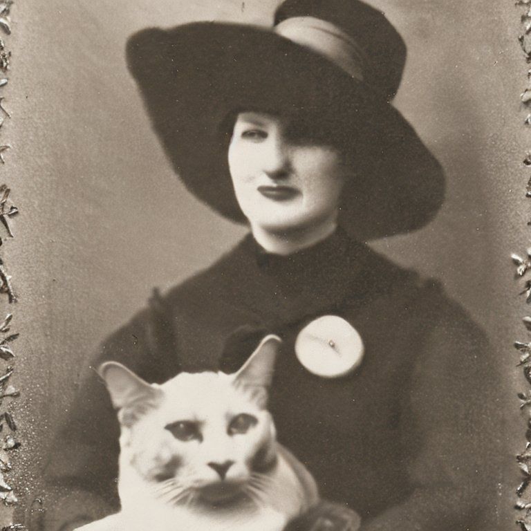 An 1800’s gelatin silver style photograph of a linguist woman wearing a hat and his pet cat