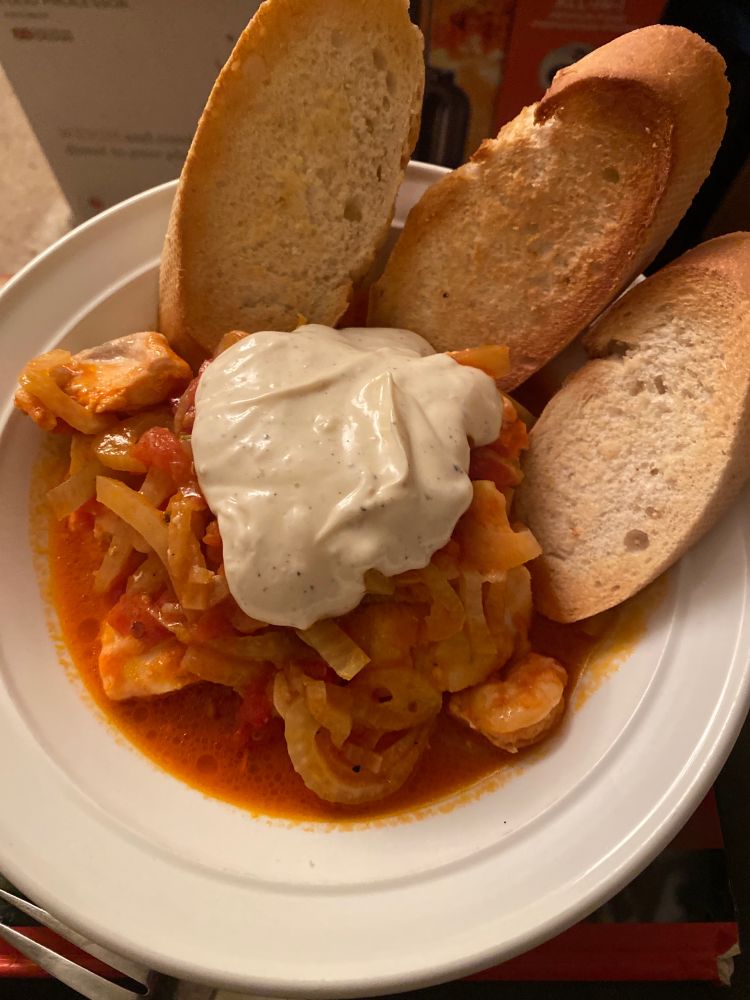White bowl, tomato and fennel and fish topped with aioli, three slices of garlic baguette