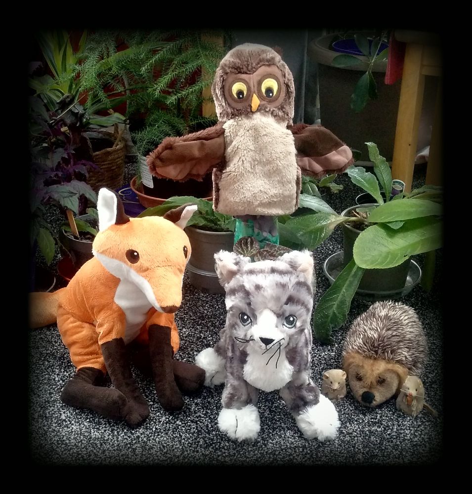 Soft toys: fox, owl, cat, hedgehog and mice, with plants in the background.