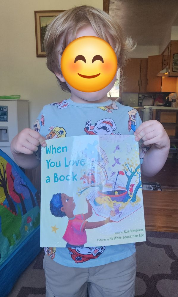 Image of a child holding the book When You Love a Book by Kaz Windness and Heather Brockmam Lee