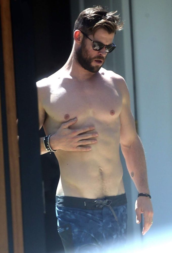 chris hemsworth seductively placing a hand on his perfectly muscular body while being shirtless for all his muscles to be on display