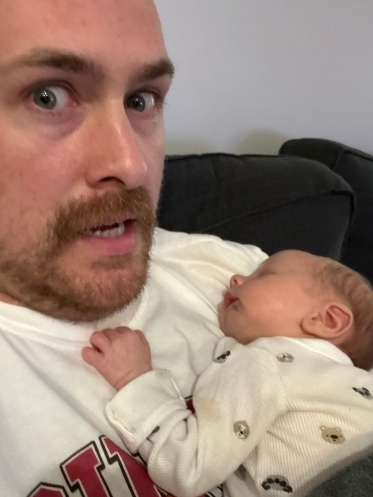 Picture of me with a tense face with a baby laying on my chest