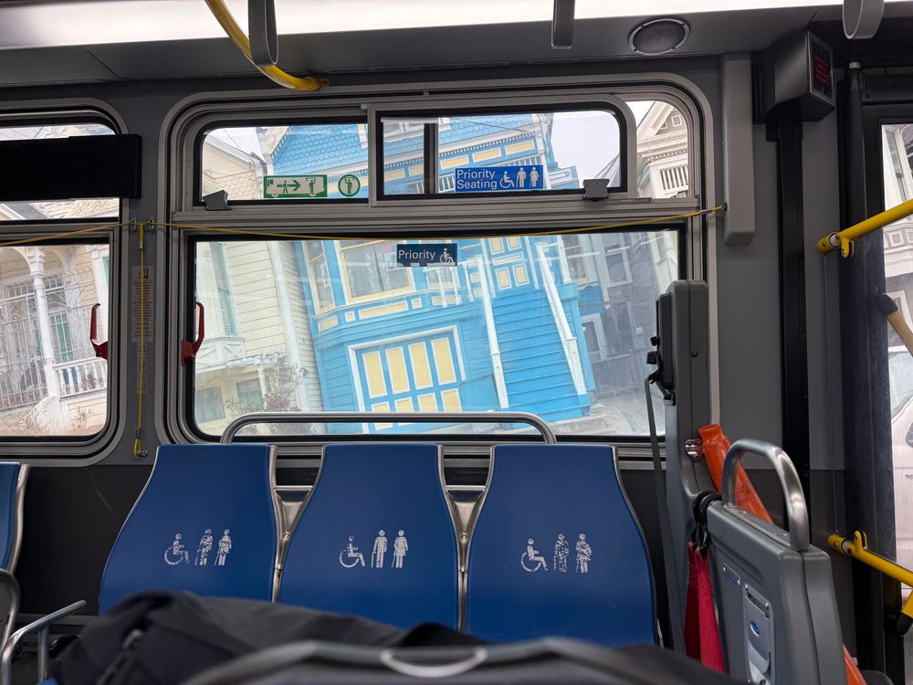 Shot inside the bus aligned with the bus, with the outside of a blue house at a crazy angle going uphill 