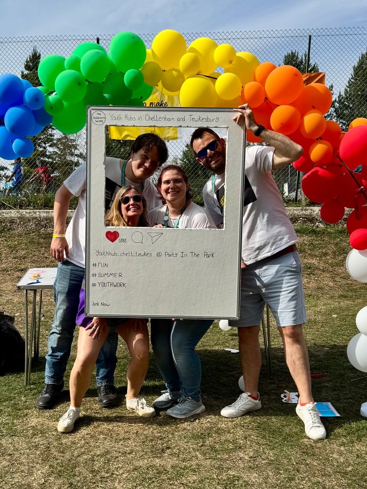 Four people from The Children’s Society behind a selfie board in front of some balloons 
