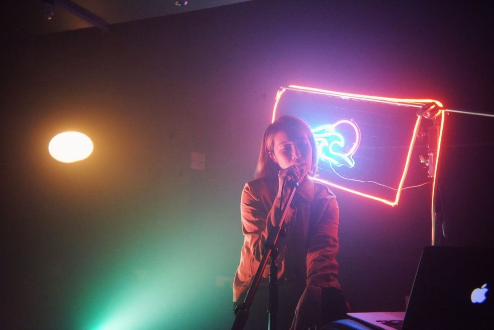 Actress sitting in front of colourful light sign