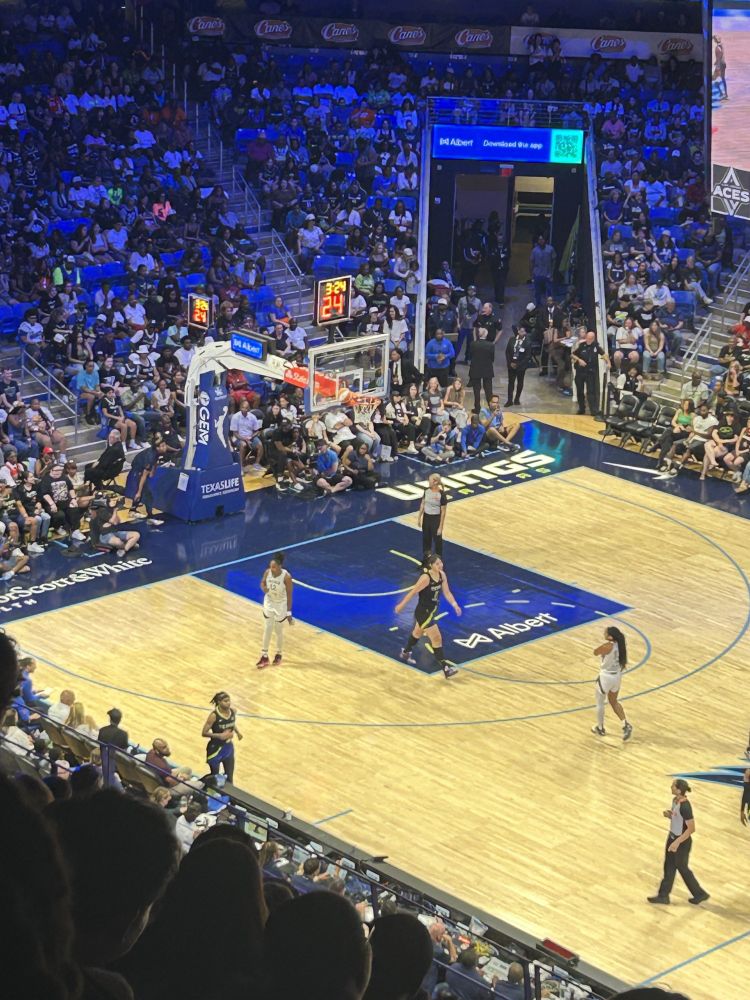 a white an orange basketball stuck in the space between the basketball hoop and the backboard, during a game between the Las Vegas Aces and the Dallas Wings on July 27th 2025