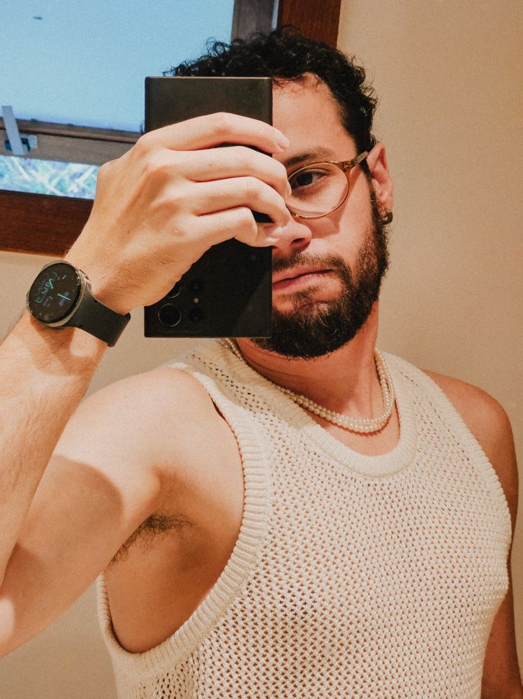 uma selfie no espelho, cortada do peito para cima, segurando o celular na frente do rosto, estou usando uma camiseta branca de renda 