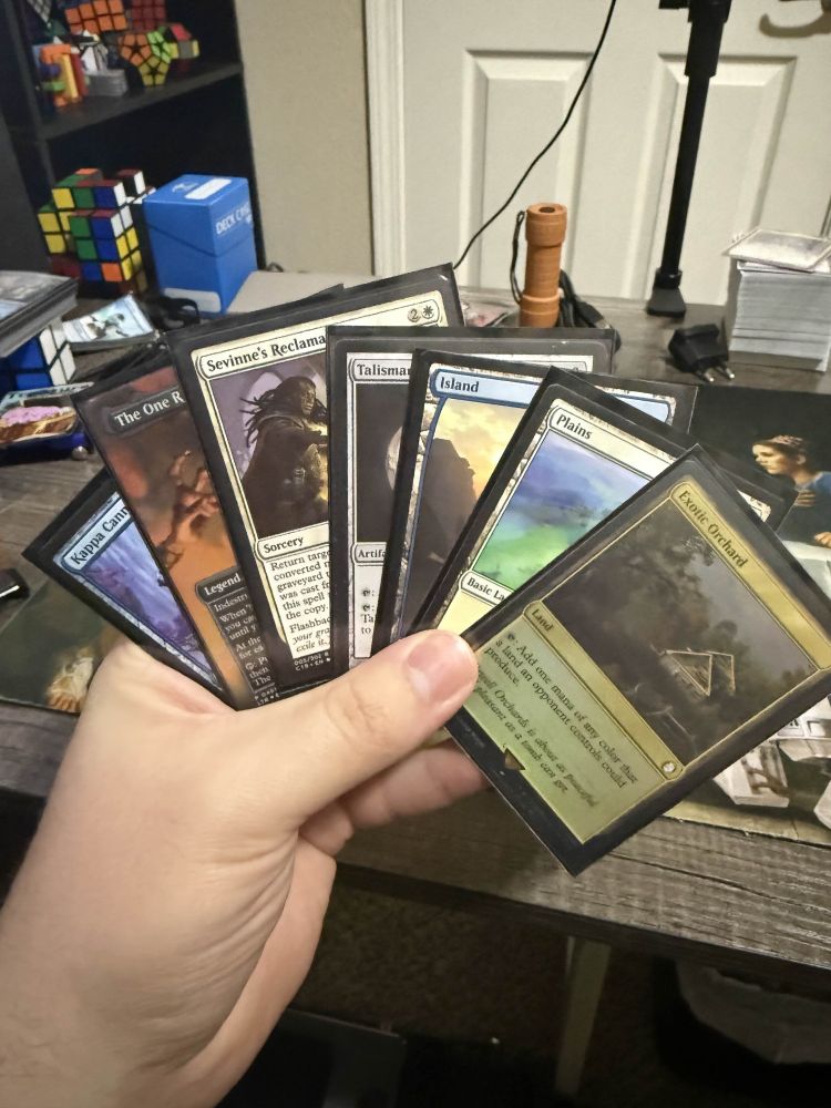 A hand of Magic the Gathering cards including an Exotic Orchard, Plains, Island, Talisman of Progress, Sevinne's Reclamation, The One Ring, and Kappa Cannoneer.