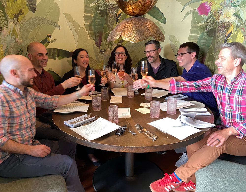 Seven people at dinner having champagne to celebrate many good things that have happened over the past year