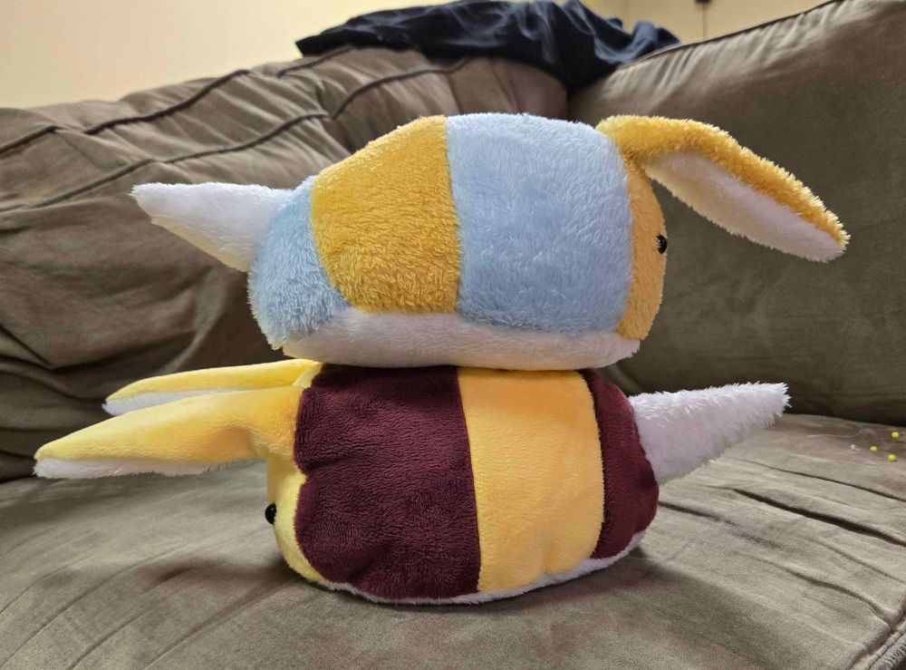 A side angle of the aforementioned "Bee Bunnies", they are stacked on one another facing opposite directions, still on the couch.