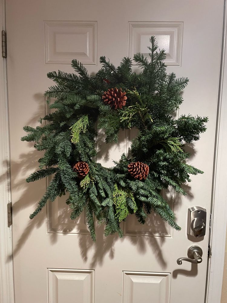 Wreath made of noble fir and other greenery hanging on a door. 