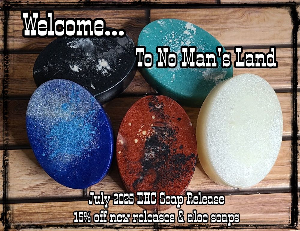 Five oval soaps on a wood panel background: one black with white, one soft turquoise with white, one blue and white, one red with black and flecks of glow powder, and one that's all white.

There is also text over the image reading "Welcome...to No Man's Land. July 2025 EHC Soap Release. 15% off new releases and aloe soaps"