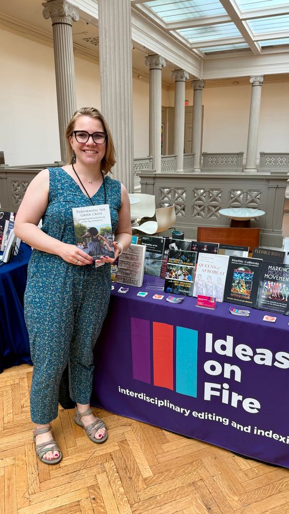 Natalie Zervou holding her book at the Ideas on Fire booth at the 2025 Dance Studies Association conference.