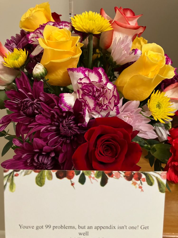 Yellow/red roses and various other flowers, with a note that reads, “You’ve got 99 problems, but an appendix isn’t one! Get well.”