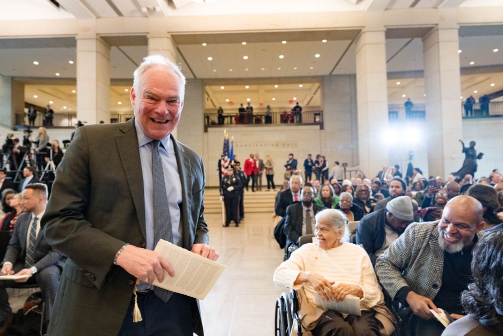 Senator Kaine poses, smiling, in front of a packed audience for the unveiling ceremony.  
