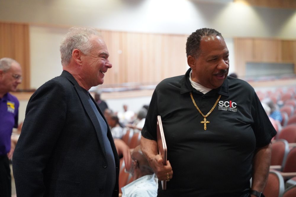 Senator Kaine smiles and chats with a man. 