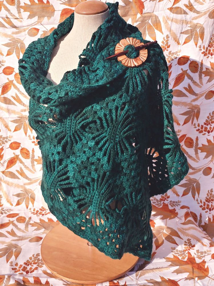 Photograph of a deep forest green shawl draped artfully on a mannequin. 