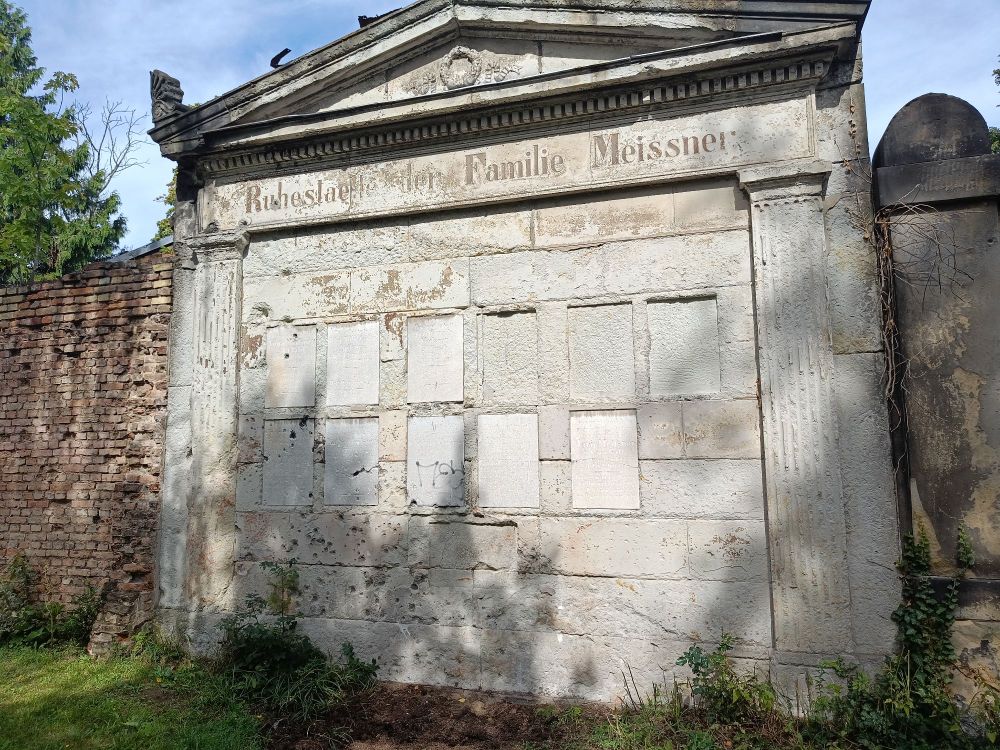 A mausoleum in a graveyard with bulletholes.