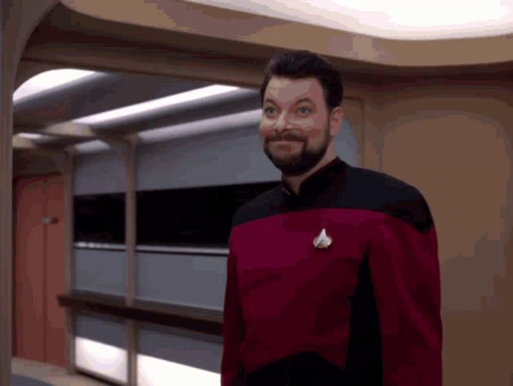 a man with a beard is wearing a red and black uniform with a star trek logo on his chest