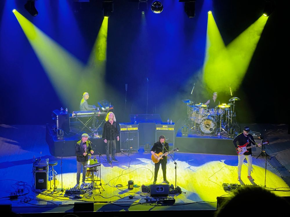 Steve Hackett and band on stage with yellow and blue lights. 