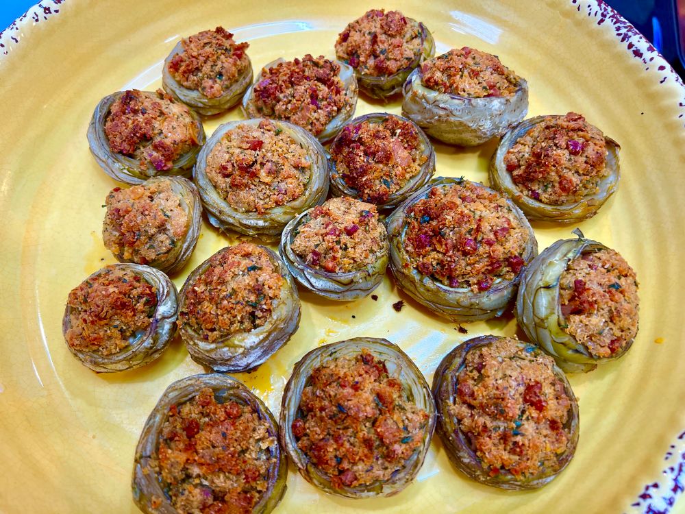 A serving dish filled with baked stuffed artichoke bottoms. 